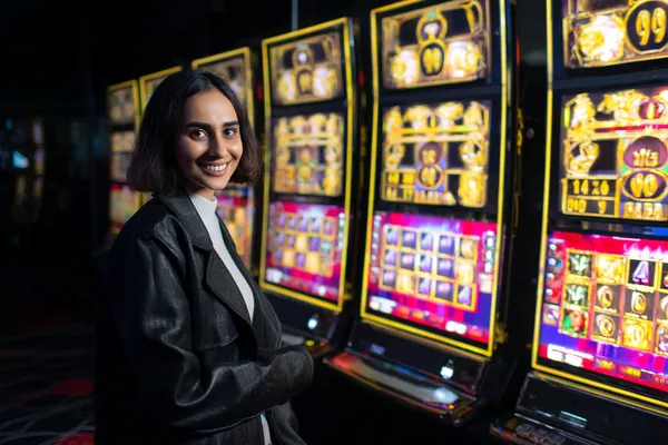 A woman smiling while playing online games on her laptop, surrounded by neon casino elements, showcasing CROWNDB’s diverse game collection.